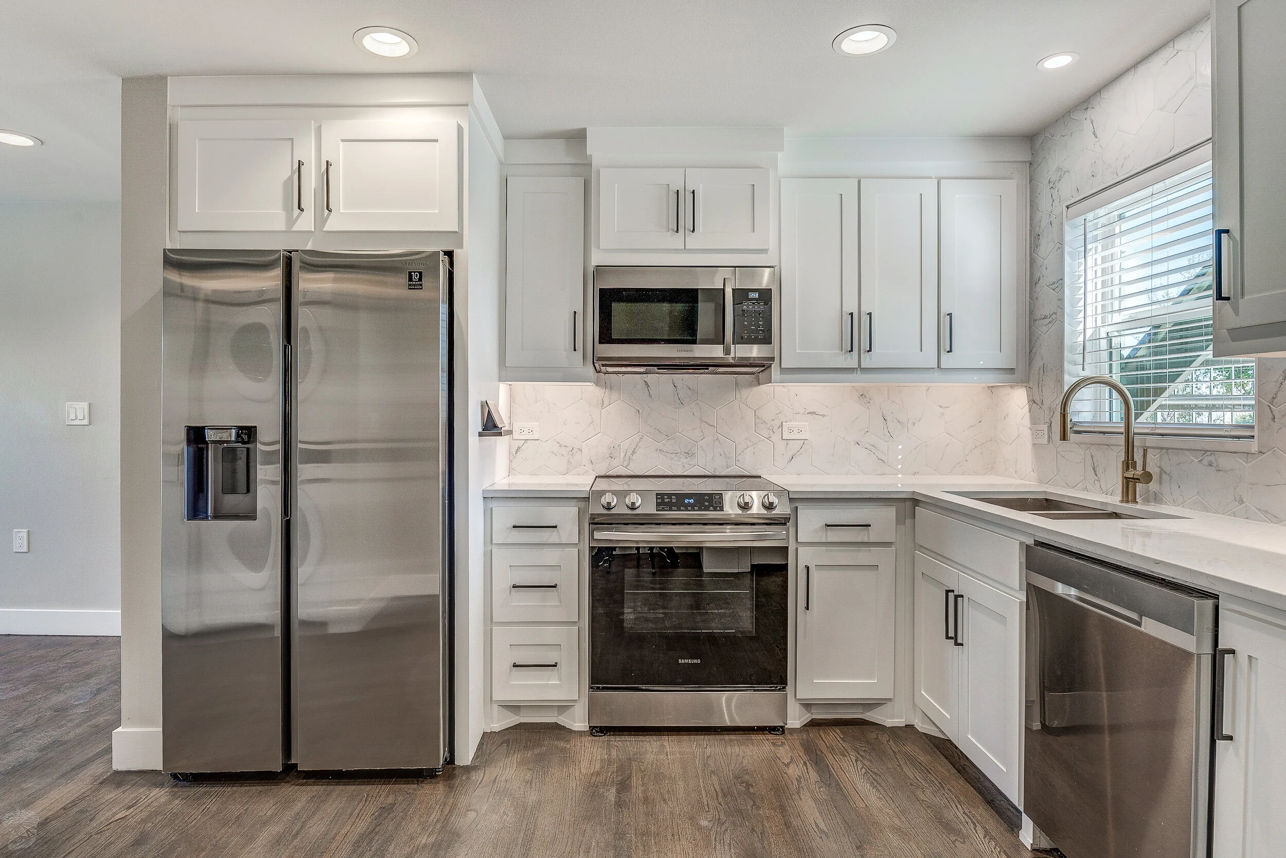 Renovated White Rock Views kitchen with white cabinetry, quartz surfaces, and stainless appliances